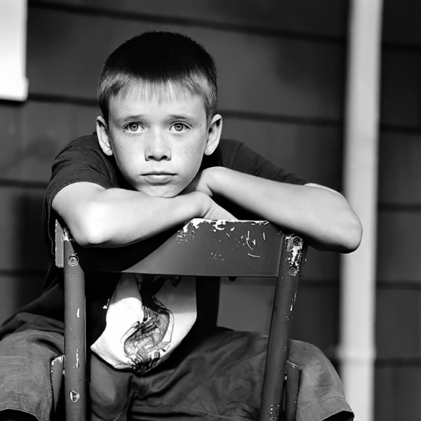 B&amp;W portrait on young boy looking directly at camera sitting backwards in chair- Frank Marchese Photography